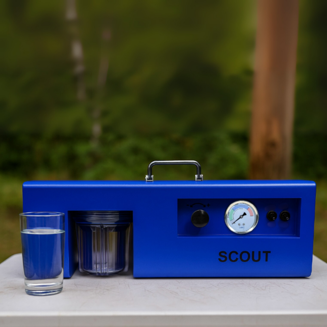 Blue device labeled 'SCOUT' with a glass of water and container on a table outdoors.